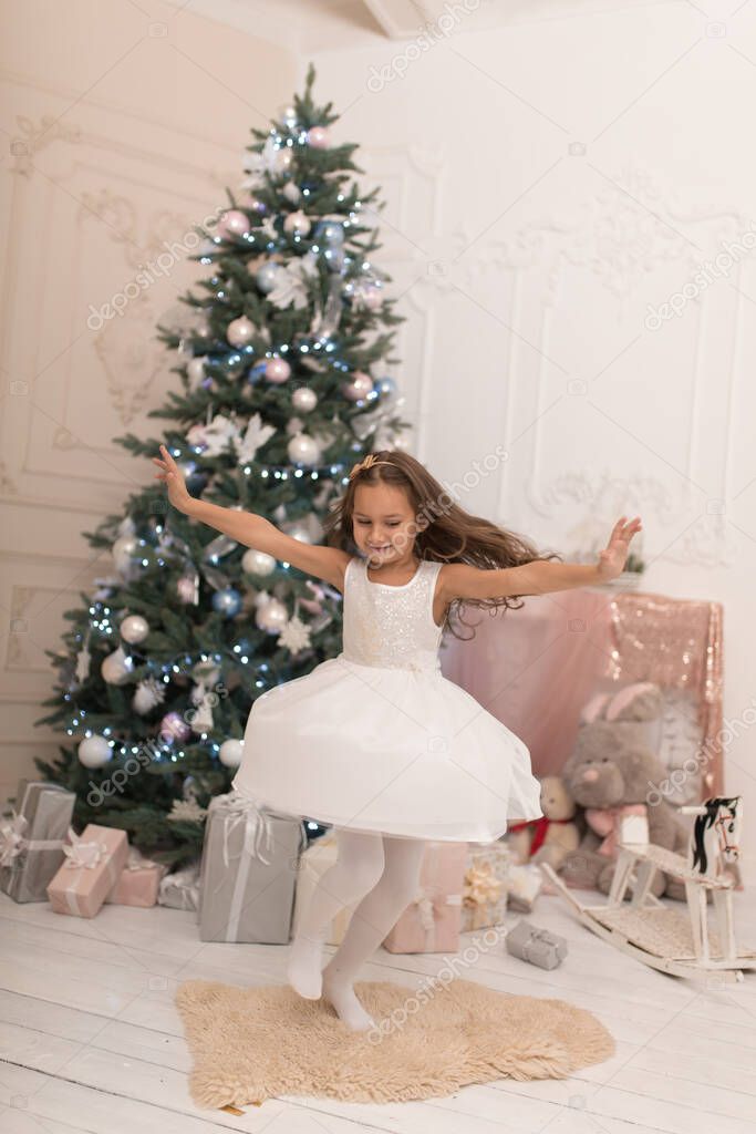 Beautiful little girl posing near the Christmas tree.
