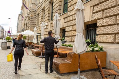 Restoran personeli restoranın yaz terasında çiçekleri suluyor. Berlin, Almanya - 05.17.2019