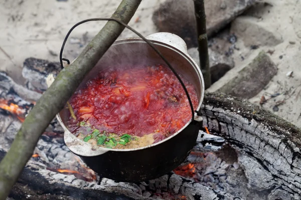 Borscht cooking in sooty cauldron on campfire — Stock Photo, Image