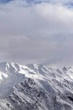 Güneş ışığı karlı dağlar ve bulutlu gökyüzü