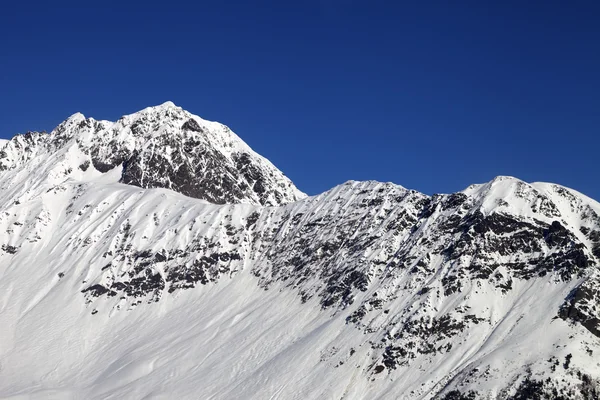 Montañas nevadas y un cielo azul claro en el día del sol frío —  Fotos de Stock