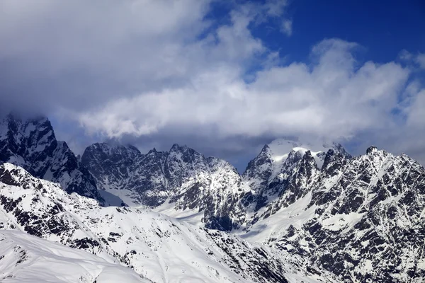 Rocce innevate in nuvole al giorno pieno di sole — Foto Stock