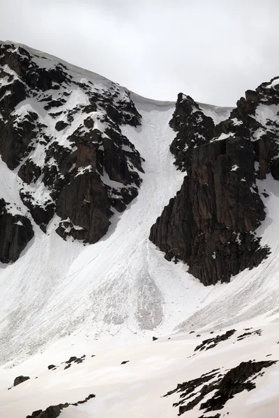 Rocks with snow cornices and traces from avalanches — Stock Photo, Image