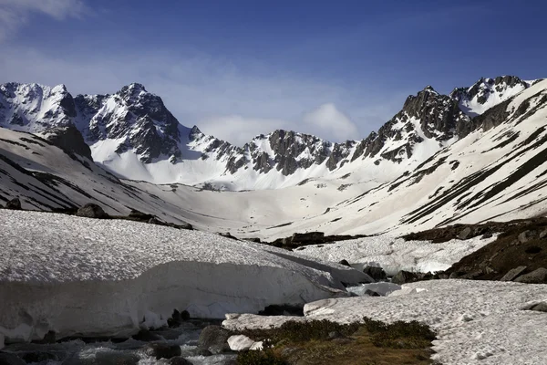 Río con puentes de nieve en las montañas de primavera en la mañana de sol — Foto de Stock