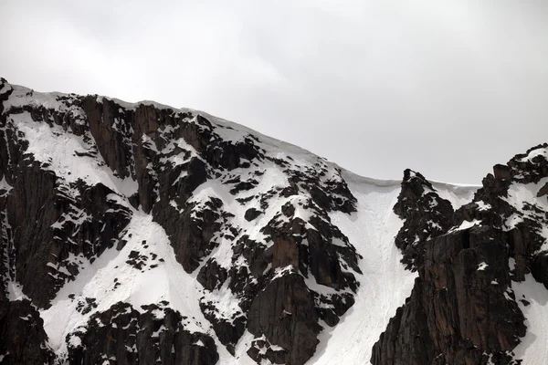 Скалы с карнизом снег в серый день — стоковое фото