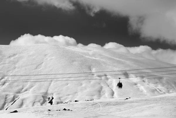 Black and white view of gondola lift and off-piste slope at evening. Caucasus Mountains, Georgia, region Gudauri.