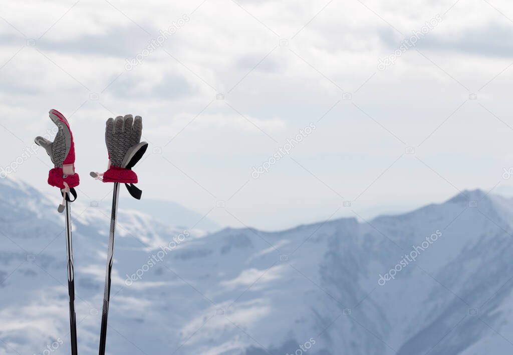 Ladies gloves on ski poles and snow winter mountains in background. Caucasus Mountains. Georgia, region Gudauri.