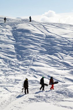 Snowboardcular soğuk bir sabahta karda yürür. Kışın Kafkasya Dağları, Gürcistan, Gudauri bölgesi.