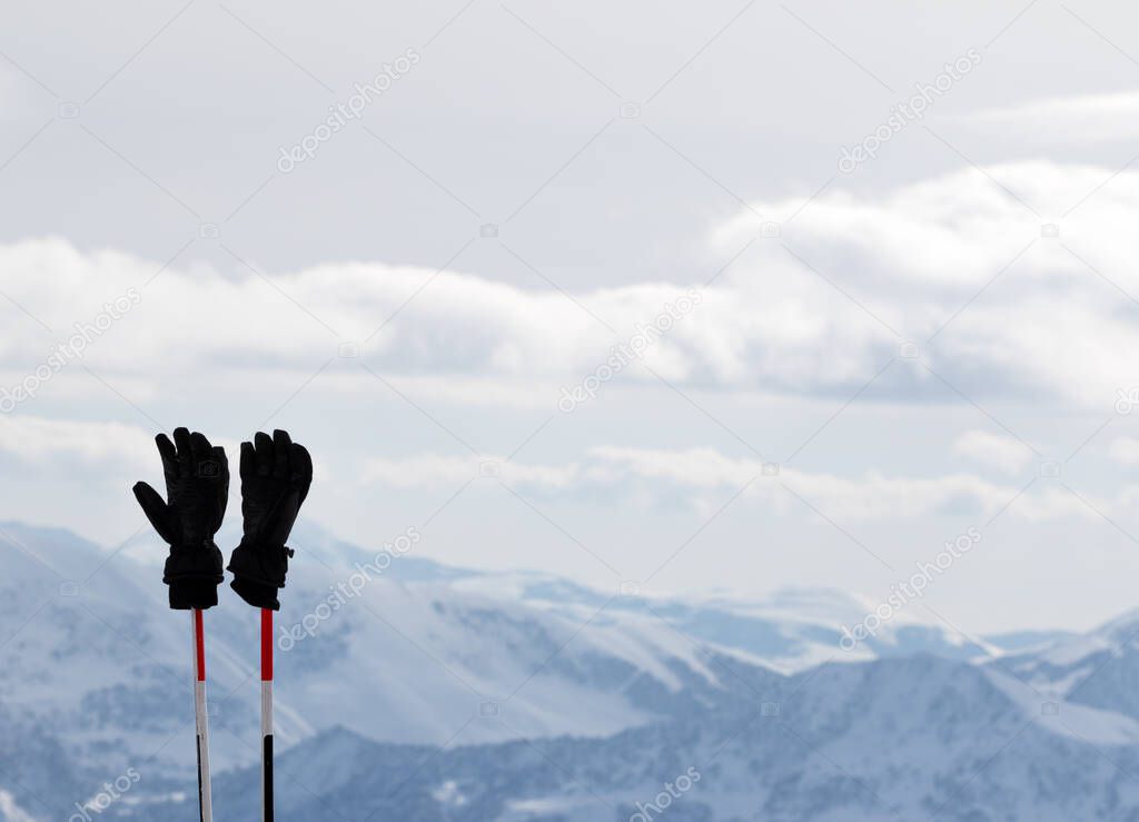 Black men's gloves on ski poles and snow winter mountains in background. Caucasus Mountains. Georgia, region Gudauri.