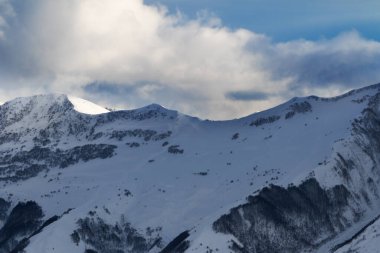 Orman ve kış akşamları bulutlu güneş ışığı olan yamaçtan manzarayı seyret. Kafkas Dağları. Gürcistan, bölge Gudauri.