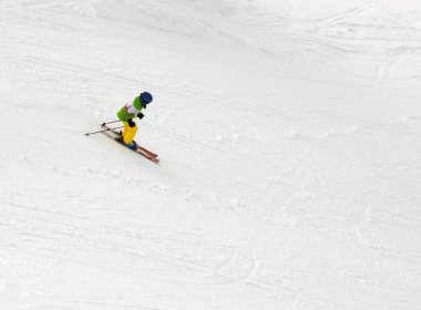 Little skier on ski slope at winter day clipart
