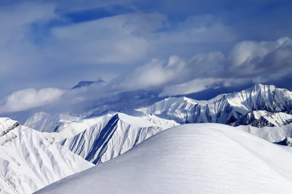 Off-piste besneeuwde helling en bewolkt bergen — Stockfoto