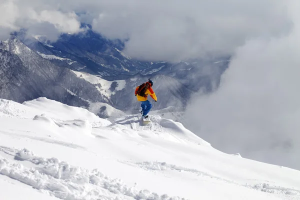 Snowboarder en pendiente fuera de pista por montañas en la niebla — Foto de Stock