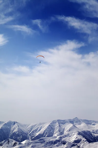 Sunlight mountain with clouds and silhouette of paraglider — Stock Photo, Image