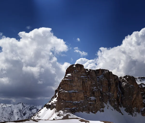 Panorama of snowy rocks and sky with sunbeam in nice spring day — Stock Photo, Image