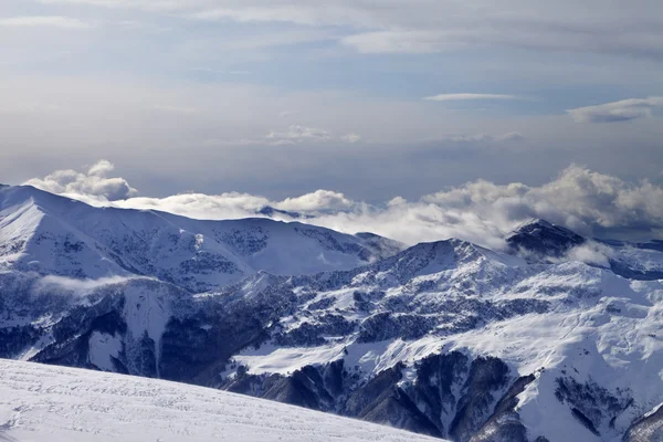 Montañas de invierno en las nubes y pista de esquí —  Fotos de Stock