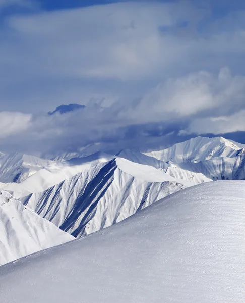 Top of off-piste snowy slope and cloud mountains — Stock Photo, Image