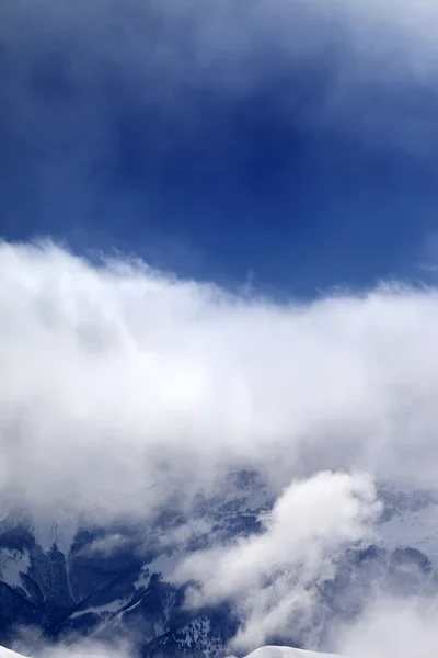 Snowy mountains in clouds at sun day — Stock Photo, Image