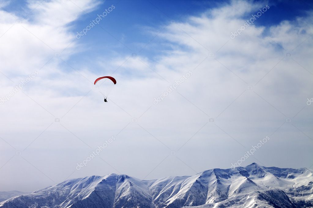 Paraglider silhouette of mountains in windy sky
