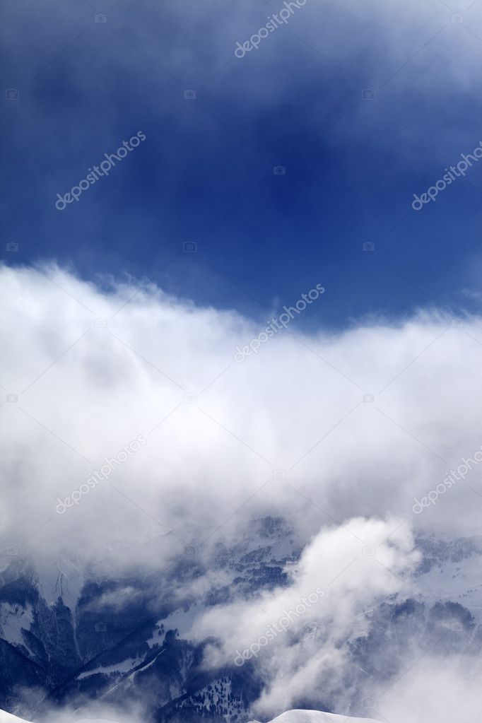 Snowy mountains in clouds at sun day