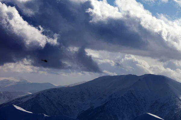 Helikopter i vinter berg och molnig himmel i kväll — Stockfoto