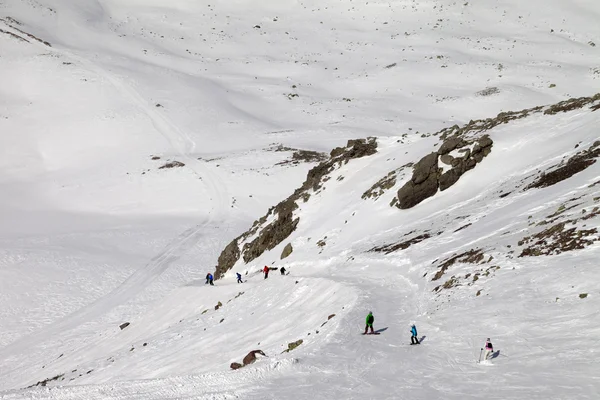 Snowboarder e sciatori sulla pista da sci al giorno del sole — Foto Stock