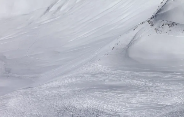 Pendiente fuera de pista con rastros de esquís y snowboards en día del sol — Foto de Stock