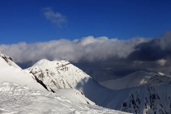 Pente de hors-piste ensoleillée et les montagnes de nuages sombres — Photo