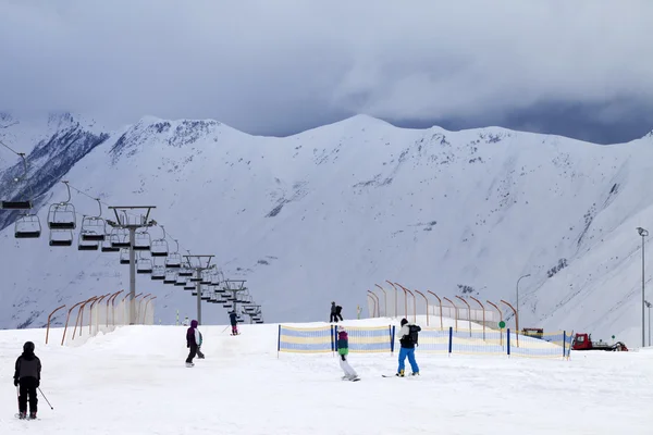 Sjezdovka lyžařů a snowboardistů v večer — Stock fotografie