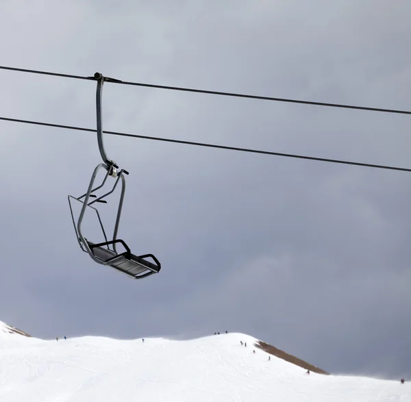 Stoeltjeslift en off-piste helling op grijze winderige dag — Stockfoto