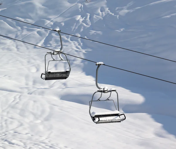 Zwei Sesselbahn mit Schneewehe und Off-Piste-Gefälle in der Sonne am Morgen — Stockfoto