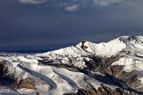 Montanhas de inverno em tarde de sol e nuvens escuras — Fotografia de Stock