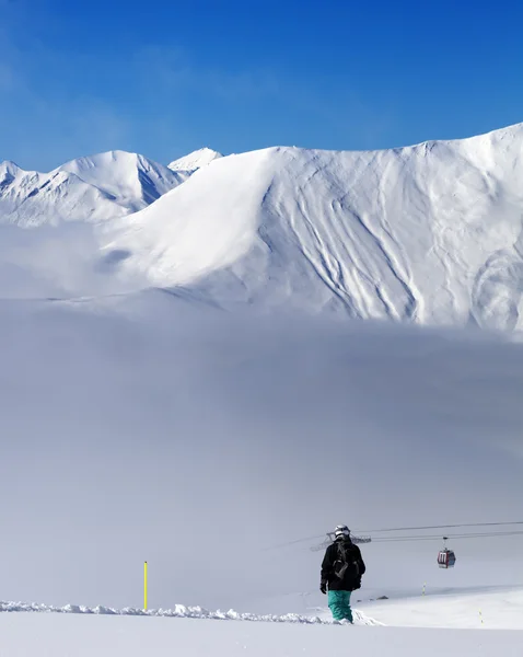 Snowboarder em declive fora de pista e montanhas em forma de neblina — Fotografia de Stock