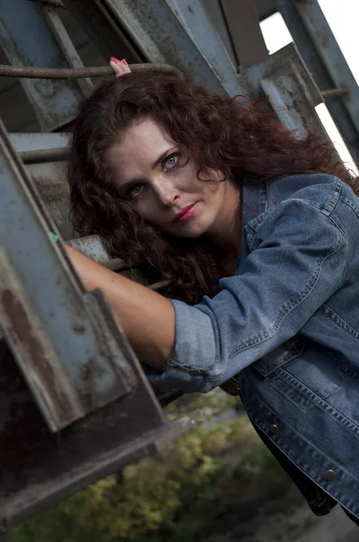 Portrait of young woman against grunge metal construction — Stock Photo, Image