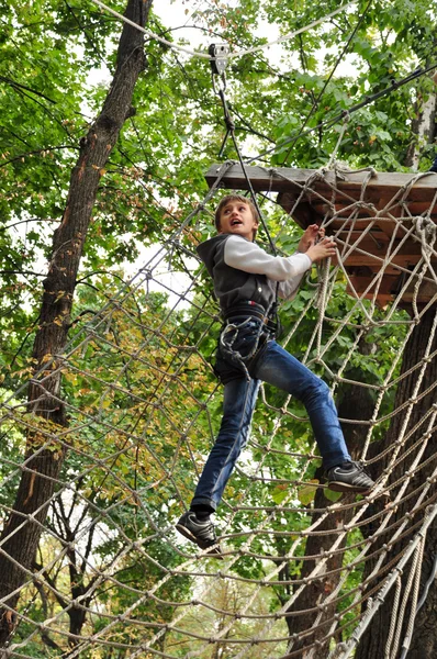 Criança em um parque de atividades de aventura de escalada — Fotografia de Stock