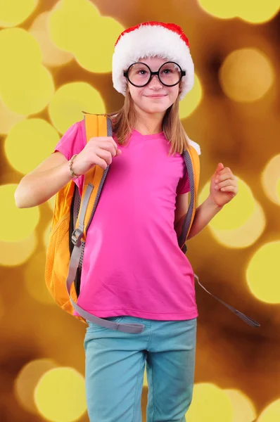 Niño con sombrero rojo de Santa Claus, mochila y gafas sobre fondo brillante — Foto de Stock