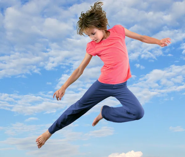 Kleines Mädchen springt und tanzt gegen blauen bewölkten Himmel — Stockfoto