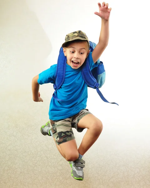 Schooljongen met rugzak springen en lopen — Stockfoto