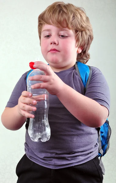 Schattige blonde schooljongen met een fles water — Stockfoto