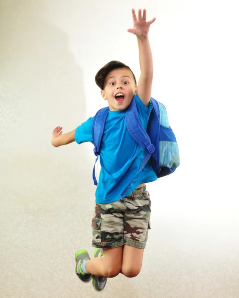 Школьник с рюкзаком прыгает и бегает — стоковое фото