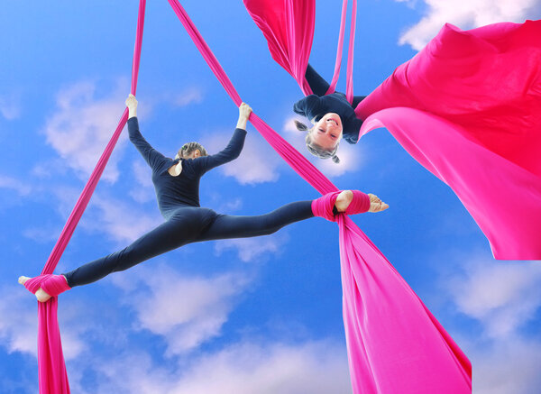 cheerful children training on aerial silks in the sky