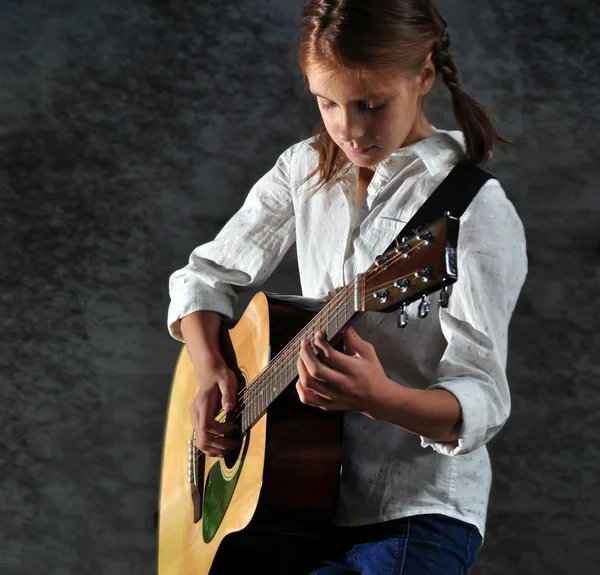 Ребенок играет на гитаре против разрушенной стены гранжа — стоковое фото