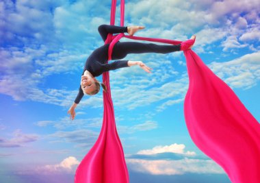 child hangs upside down on aerial silks in sky clipart