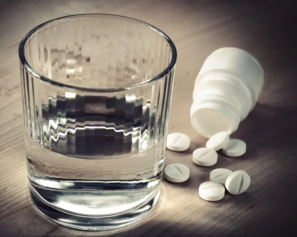Таблетки и стакан воды — стоковое фото