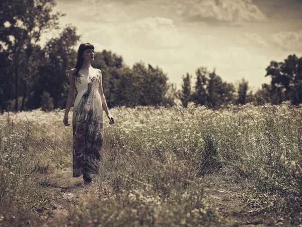 Woman walking on the meadow, retro styled portrait