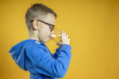 Bir çocuk turkuaz arka planda su içer.