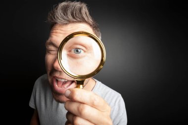 Adam siyah arka plandaki büyüteçten bakıyor. Koca adam gözü.