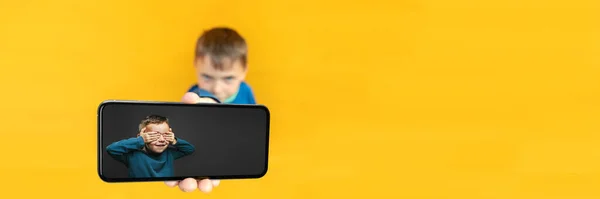 Enfant Tient Téléphone Dans Main Pour Publicité Sur Fond Jaune — Photo