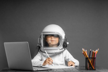 Çocuk, astronot kaskı takarak okulda uzaktan çalışıyor. Okula geri dön.