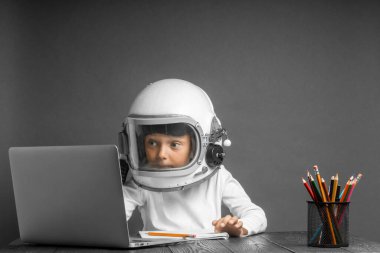Çocuk, astronot kaskı takarak okulda uzaktan çalışıyor. Okula geri dön.
